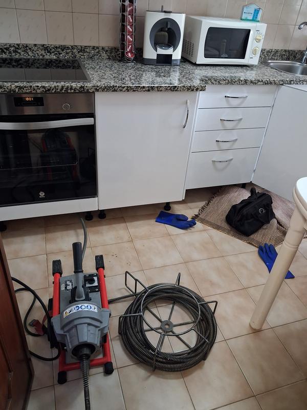 Máquina de desentupimento e cabo de mola preparados numa cozinha